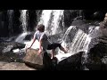 Young woman playing in waterfall on sunny day