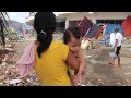 Aux Philippines, une jeune mère porte son nourrisson dans ses bras au milieu des ruines