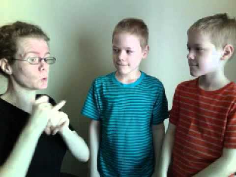 #aslday
More information at http://aslday.org and https://www.facebook.com/ASLDay1817
(A white woman wearing a black shirt appears with two young boys, wearing blue and orange striped shirts respectively.)
Hi, I'm Adrean and here are my sons. (The boy