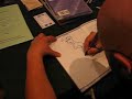 Howard Tayler sketches in a book at Dragon Con