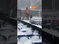 US football fans clear snow from stadium seats