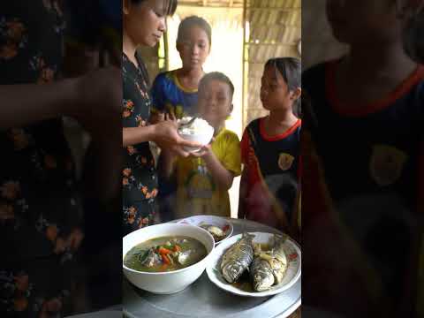Trẻ em ngồi chờ mẹ bưng cơm ra, mâm cơm có bát canh chua, đĩa cá kho