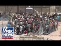 WATCH: Hundreds of migrants breach razor and rush the US border