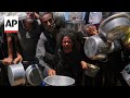 Hungry Palestinians bring pots to soup kitchen in Khan Younis to collect food