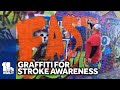 Volunteers paint graffiti to highlight stroke symptoms