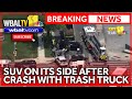 SUV turns onto side in collision with trash truck