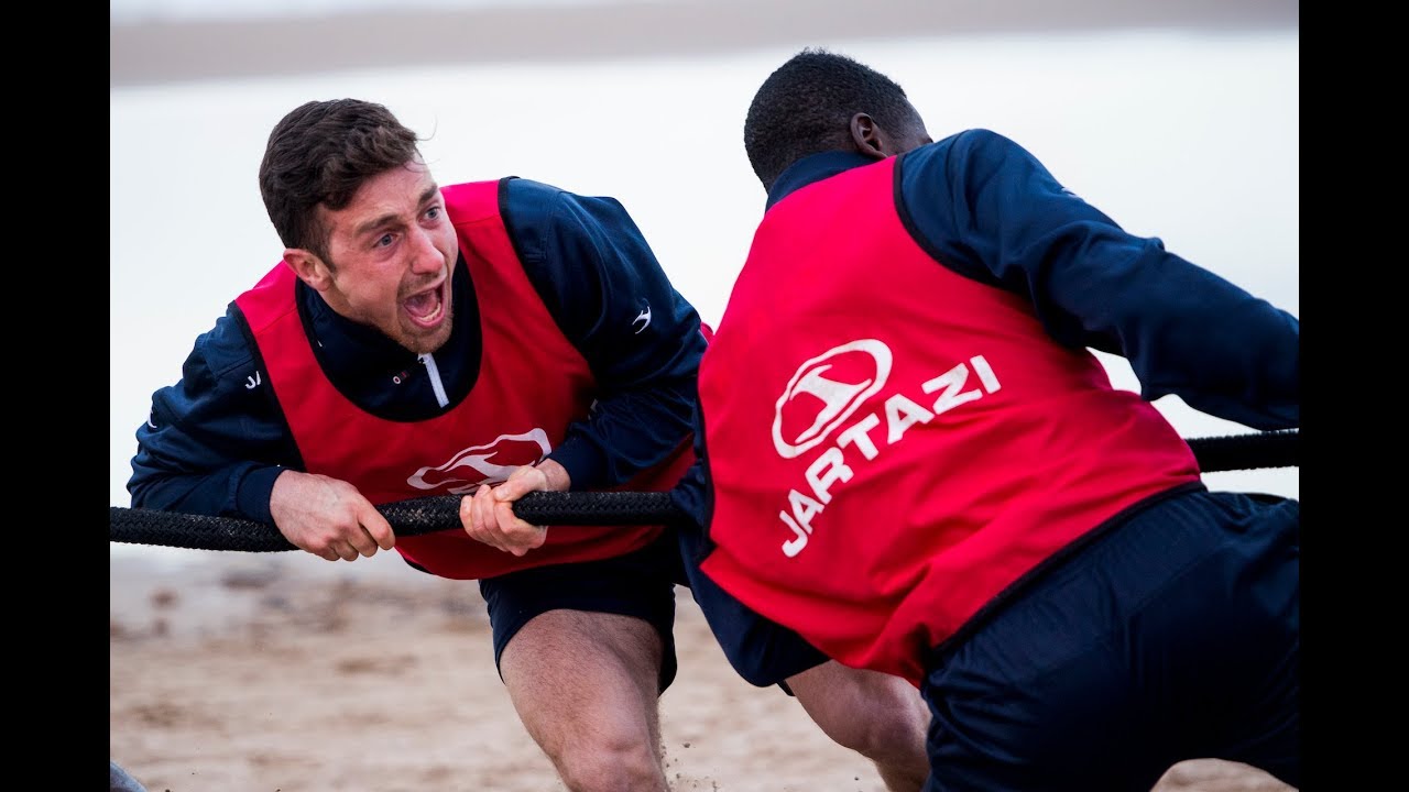 Stevige strandtraining met worstelen en touwtrekken